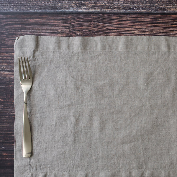 Silver fork on a textured linen placemat with a wooden surface background