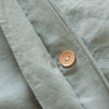 Close-up of a light green fabric with a brown button