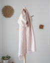 Pink striped scarf hanging on a wooden coat rack against a white wall.