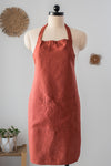 Red apron on a mannequin against a light gray wall with decorative elements.