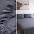 Gray fitted sheet on a bed with close-up details and a bedroom setting.