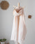 coral drizzle linen 100 percent linen scarf draped over a wooden stick against a light grey wall with decorative elements.