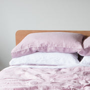 lilac linen bedding with pillows on a bed against a plain wall