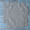 Two Natural 100% Linen Cocktail Napkins on a rustic wooden surface