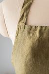 Green apron worn by a person on a neutral background
