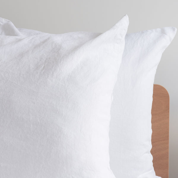 Close-up of a Pure white linen pillow with a wooden backrest on a neutral background