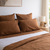 Tobacco brown bedding set on a bed with a lamp and decor in the background