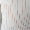 Close-up of a white pillow with brown stripes and a blurred vase in the background.