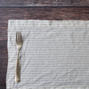Silver fork on a Natural Flax Stripe 100% Linen Placemat with a wooden surface background