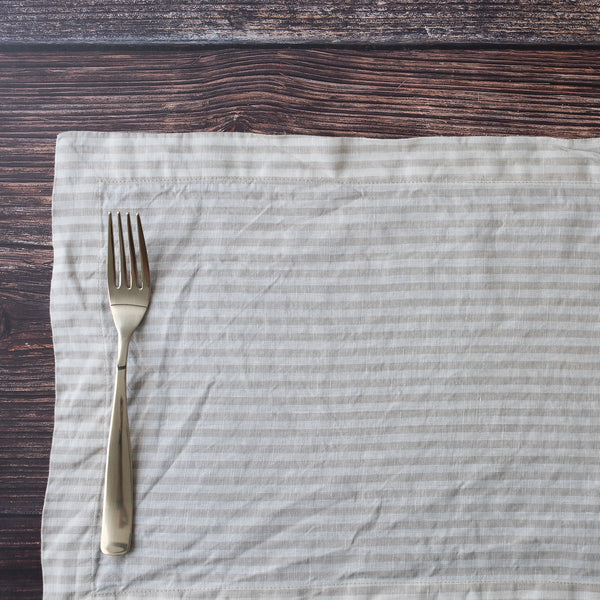 Silver fork on a Natural Flax Stripe 100% Linen Placemat with a wooden surface background