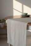 Dining table with a beige runner and a bowl on a gray background