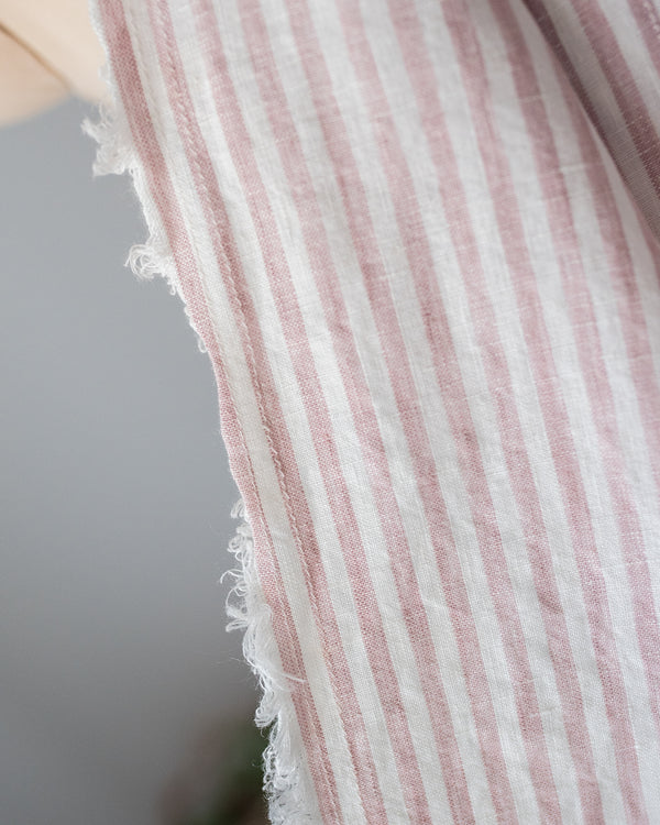 Close-up of a sleeveless garment with pink and white striped pattern on a blurred background