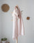 Pink striped scarf hanging on a wooden coat rack against a white wall.