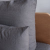 Charcoal grey European linen textured pillows on a bed with a wooden headboard.