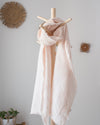 coral drizzle linen 100 percent linen scarf draped over a wooden stick against a light grey wall with decorative elements.