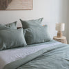 Bed with Harbour Sage linen fitted sheetand pillows in a bedroom setting.