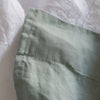 Close-up of Harbour Sage flat sheet 100% linen with a white background