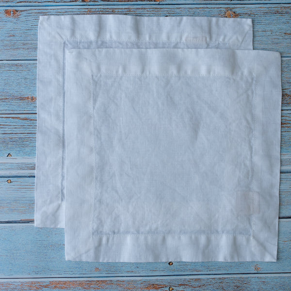 Pure White 100% Linen Cocktail Napkinson a wooden surface