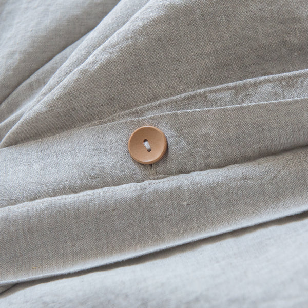 Close-up of beige fabric with a button, likely from a garment or textile product.