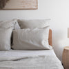 Neatly made bed withNatural linen fitted sheet and pillows in a bedroom setting.