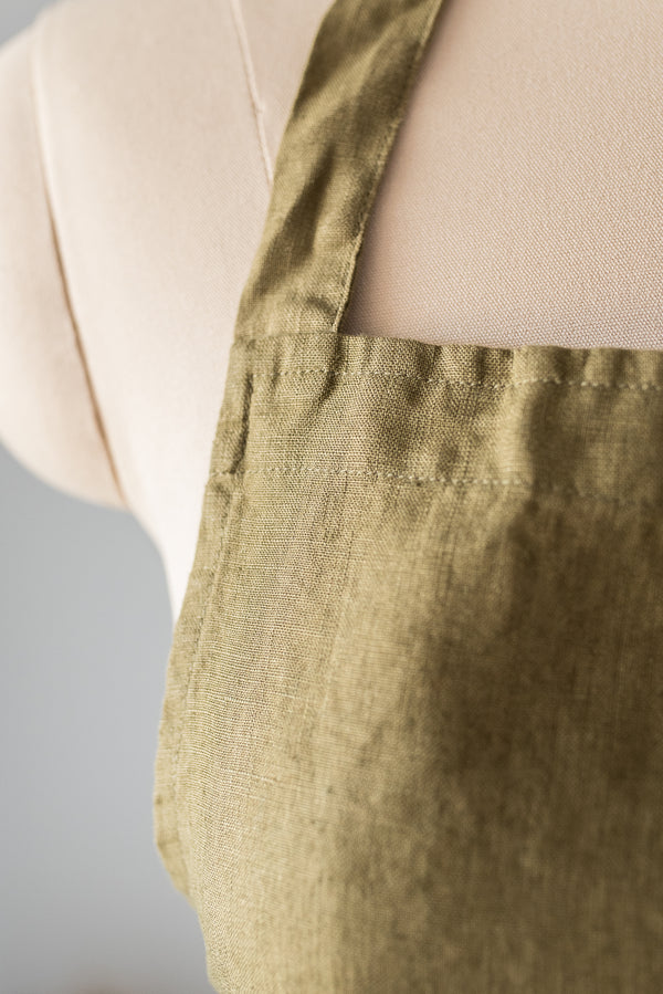 Green apron worn by a person on a neutral background