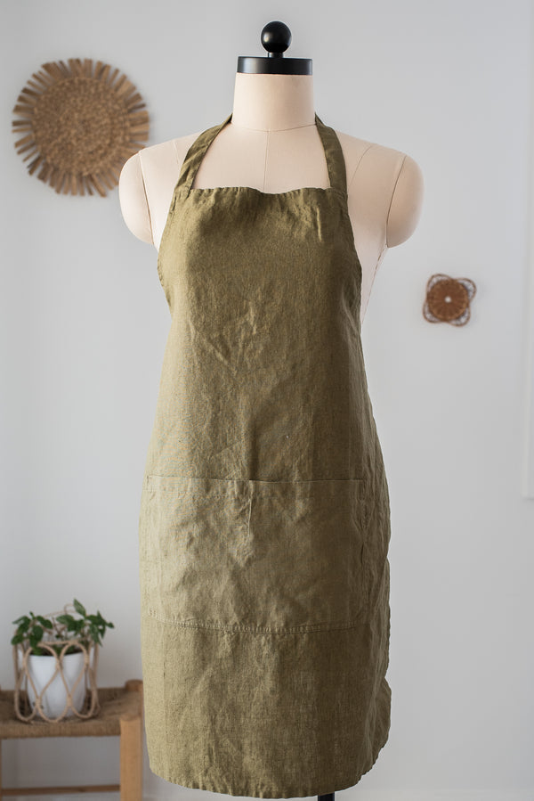 Green apron on a mannequin against a white wall with decorative elements.