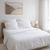 Neatly made bed with white bedding in a bright bedroom.