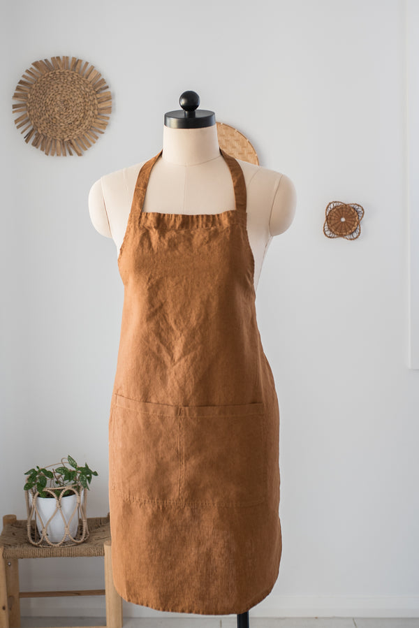 Brown apron on a mannequin against a white wall with decorative elements.